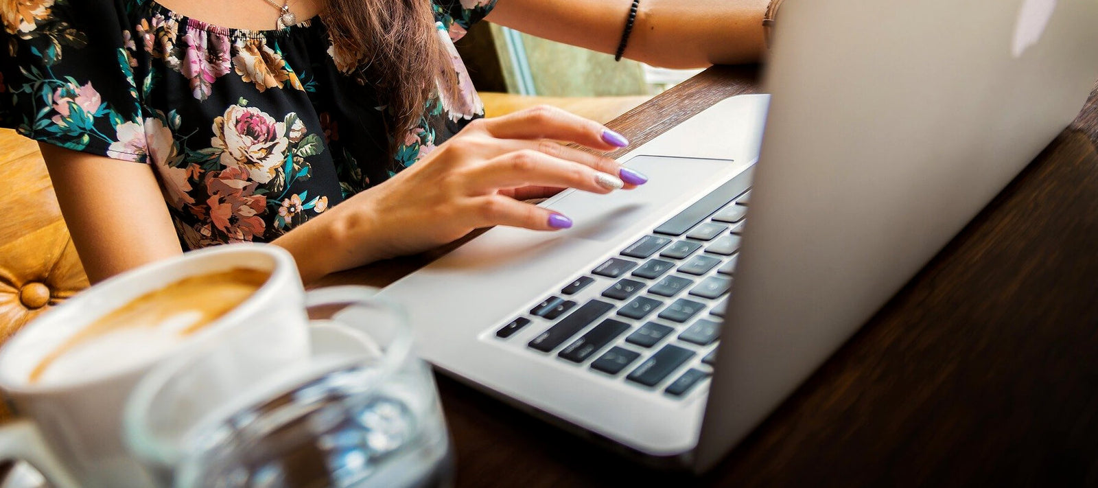 Woman tying on her laptop at her desk with coffee