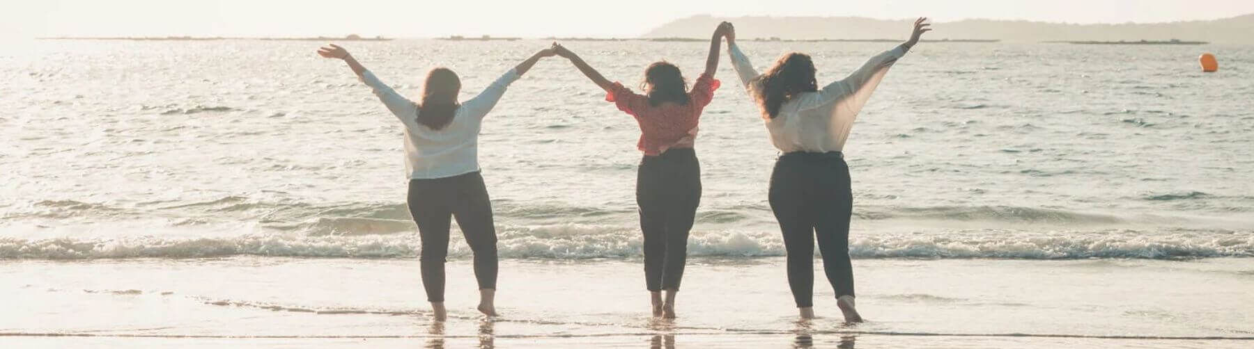 Three ladies holding hands on a beach